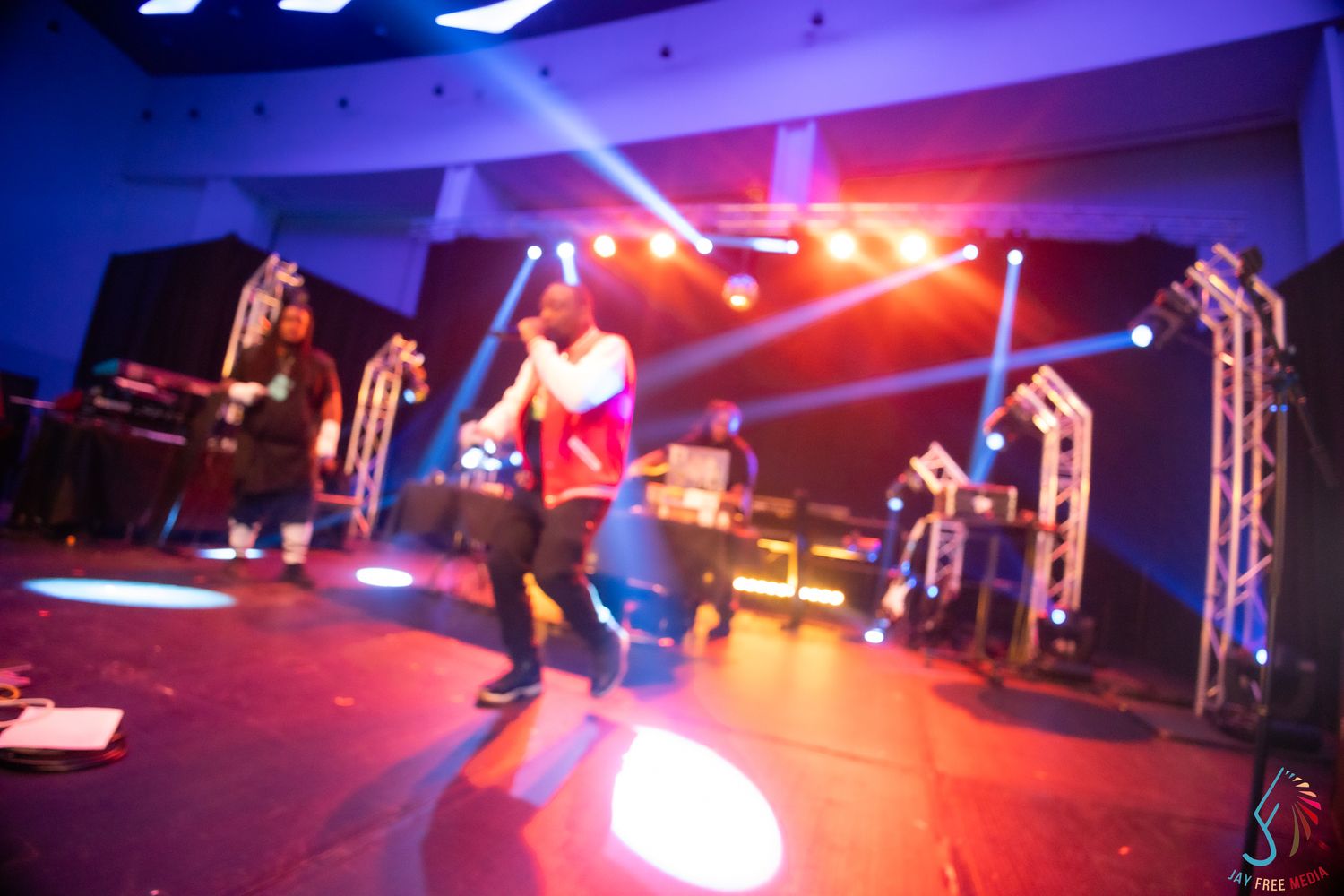 Energetic performer on a colorful stage with blue and red lights during a live music concert.