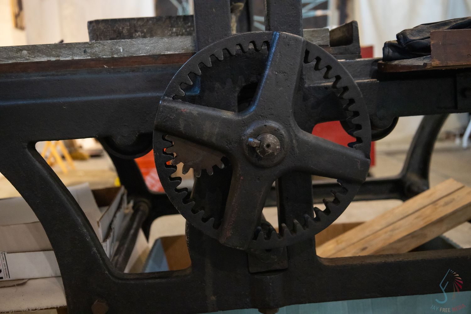 Close-up of antique cast iron interlocking gears on vintage industrial machinery in a workshop setting.