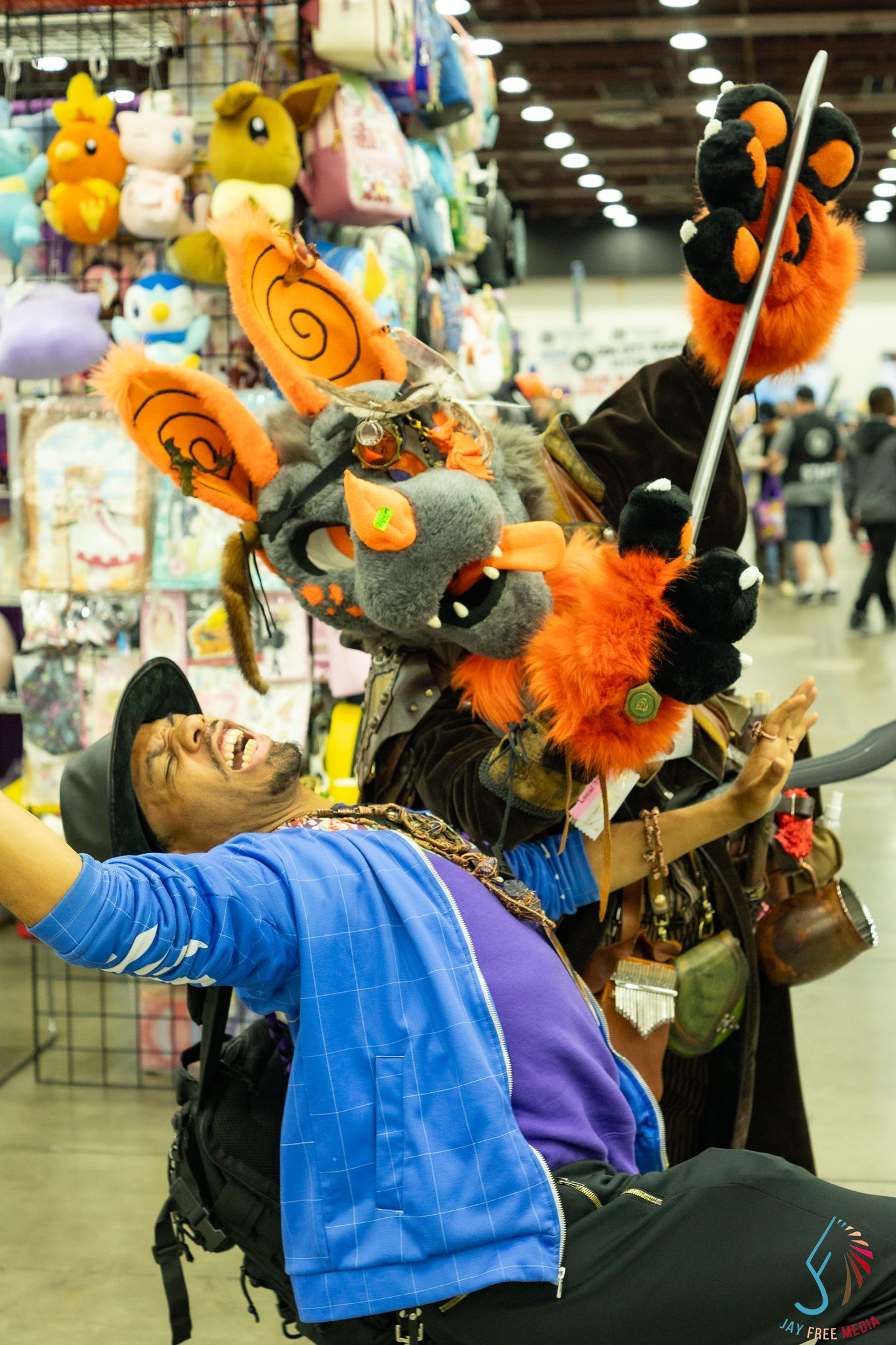 Elaborate furry costume with orange accents at an anime convention vendor hall.