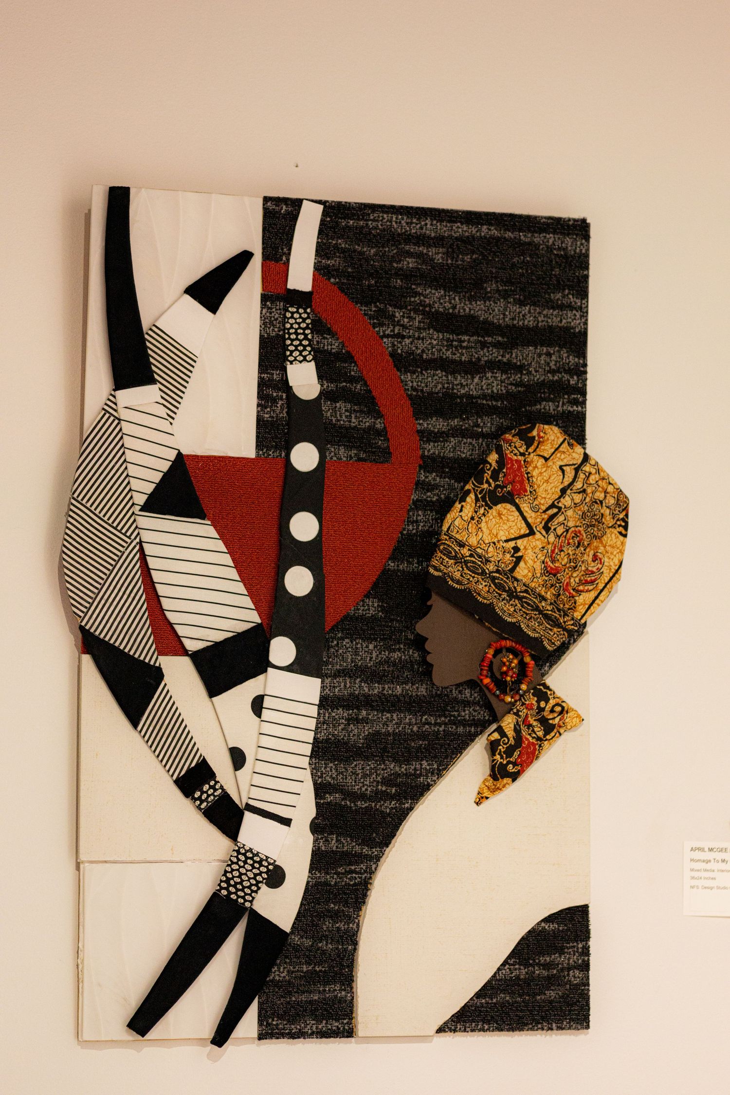 Abstract textile art piece featuring a profile of a figure wearing a colorful turban, with geometric black, white, and red patterns.