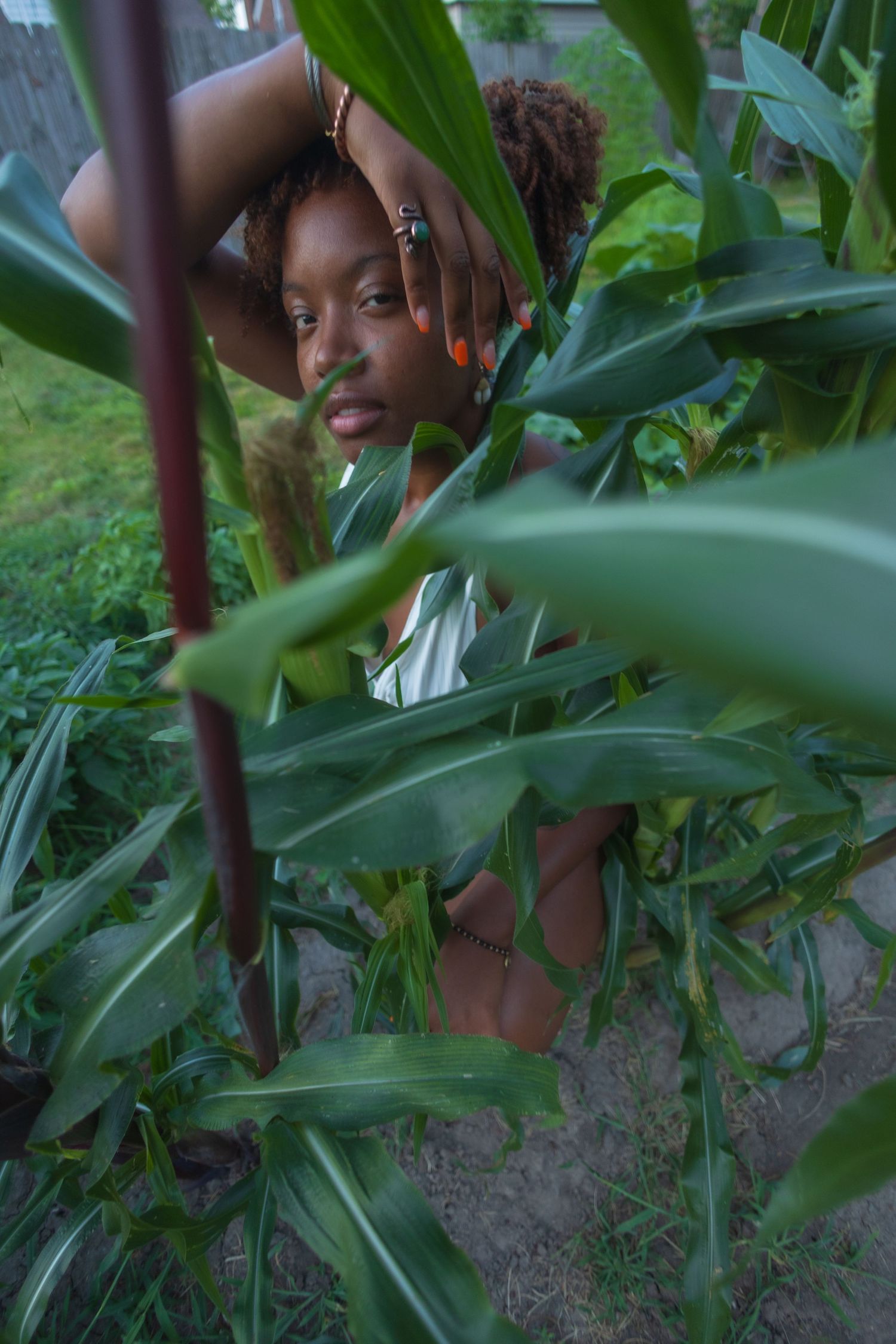 A creative portrait photograph taken through green tropical foliage, creating a natural framing effect.