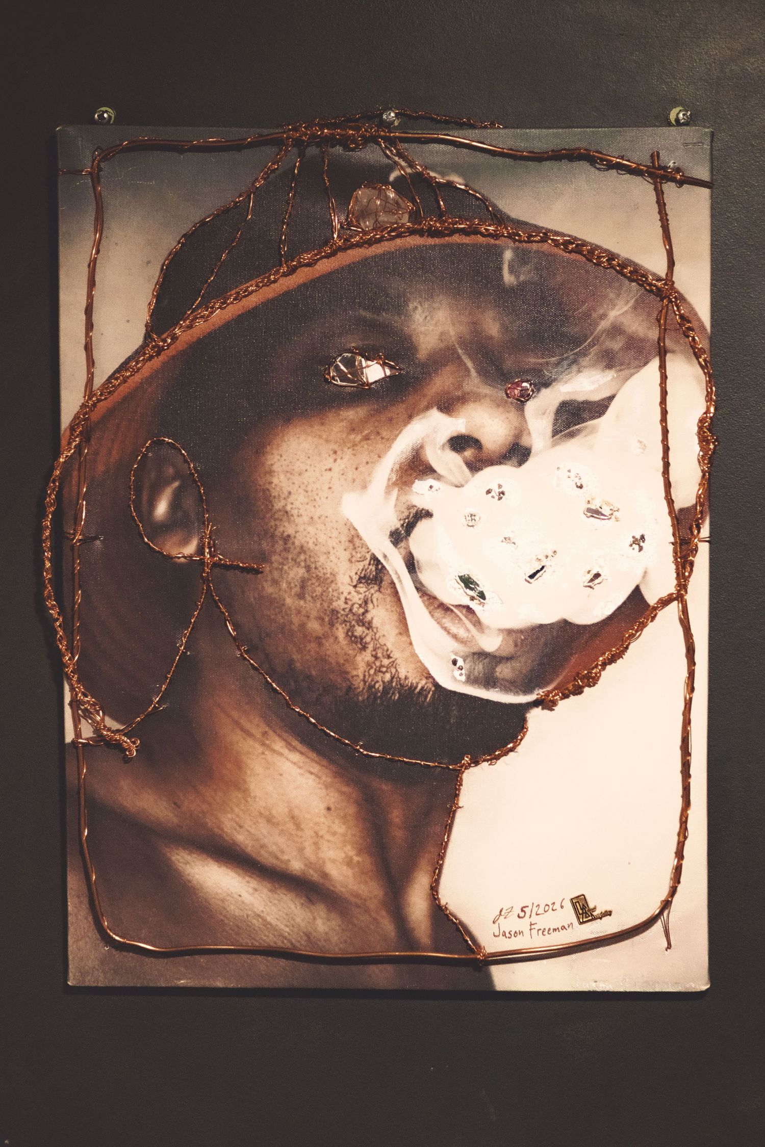 Mixed media artwork featuring a portrait of a man exhaling smoke, with burned edges and wire details on dark background.