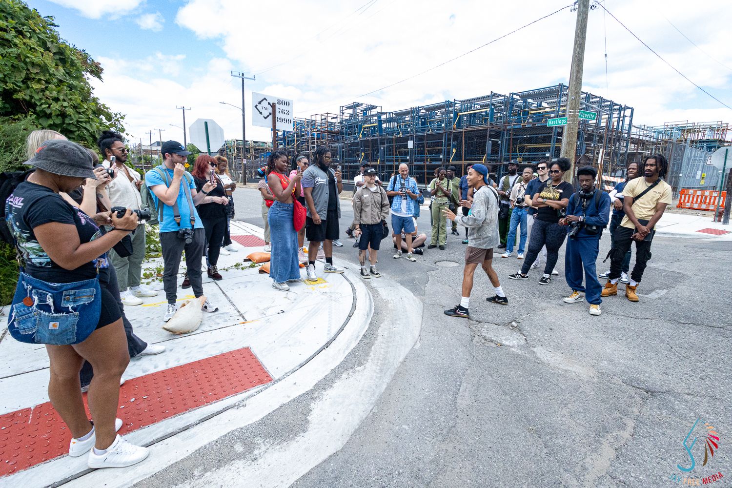 Diverse group of people gathered outdoors near urban construction site on a community tour on a cloudy day.