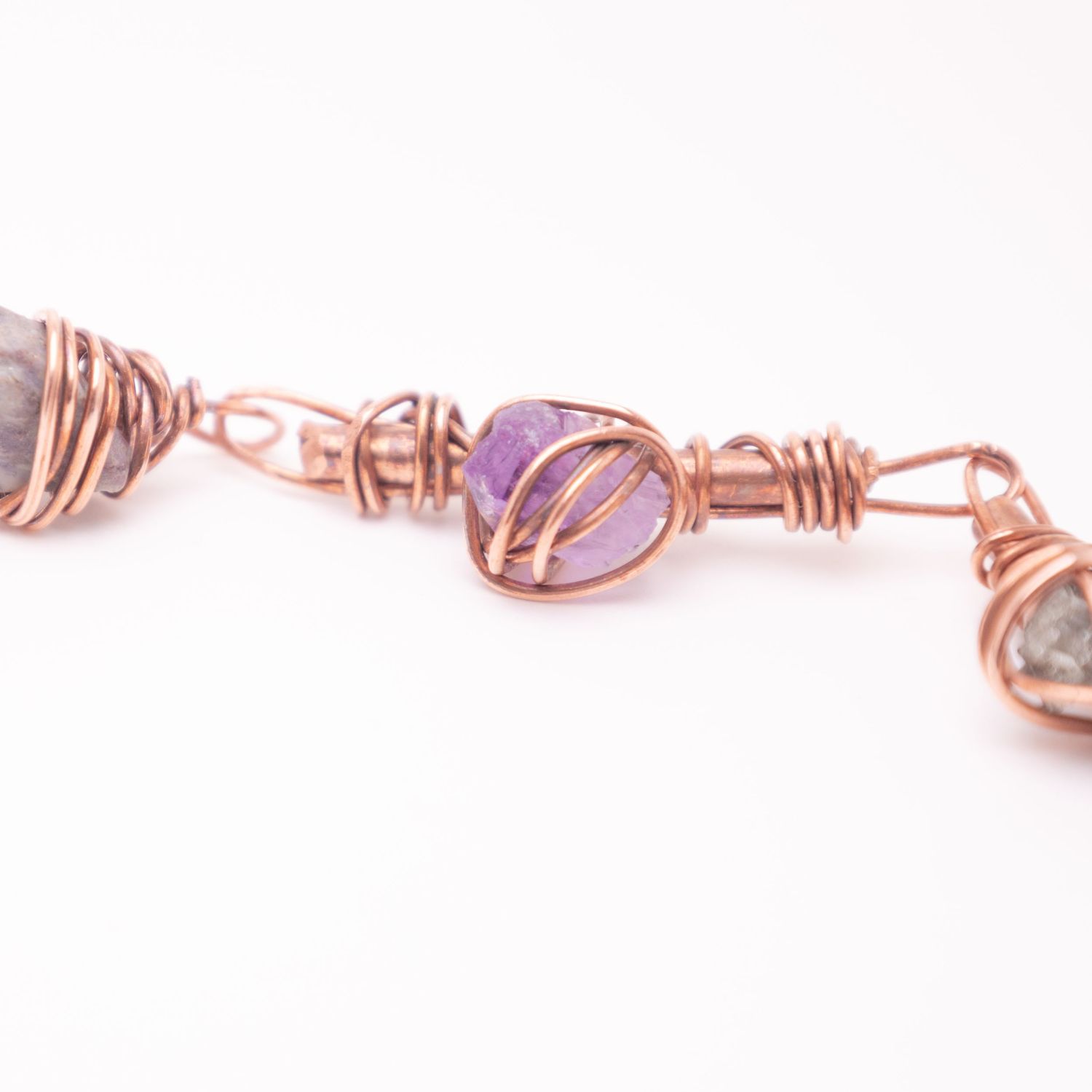 Handmade copper wire wrapped bracelet featuring purple amethyst and smoky quartz gemstones in an intricate woven design.