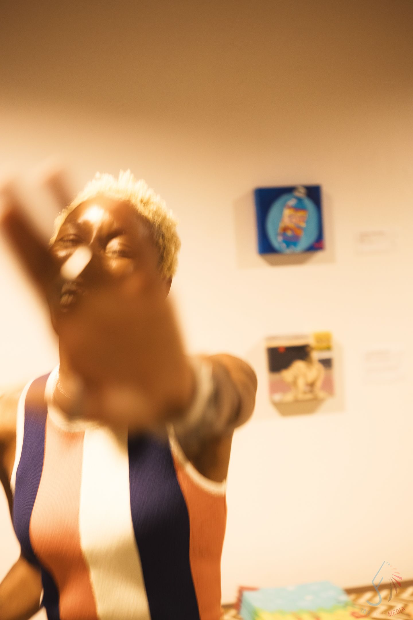 Blurred motion shot of person reaching toward camera in art gallery setting.