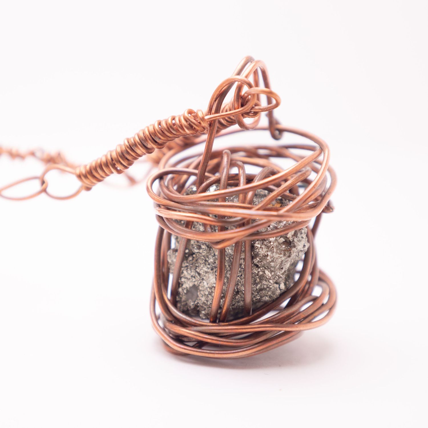 Handmade copper wire wrapped pyrite crystal pendant necklace with intricate cage design on white background.