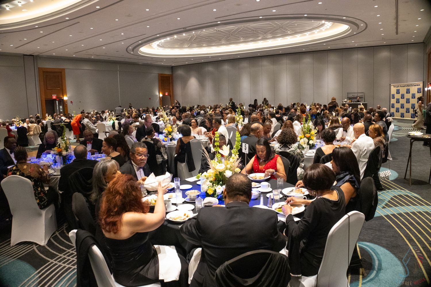 Large banquet hall filled with guests seated at round tables during a formal dinner event.