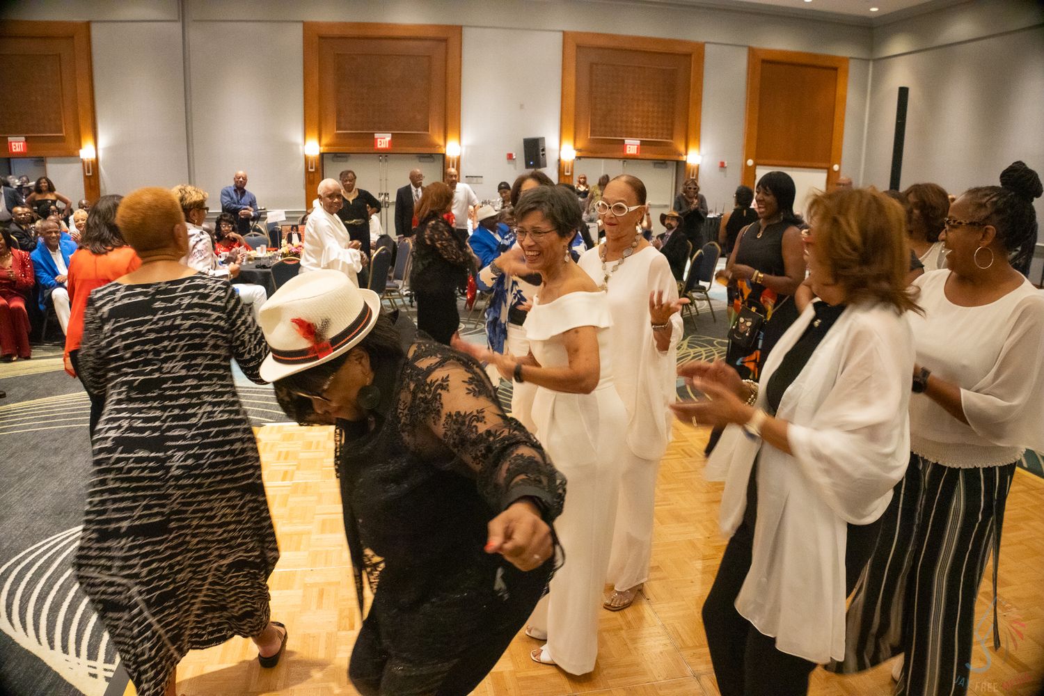 Guests dancing and socializing in a large banquet hall at a formal event.