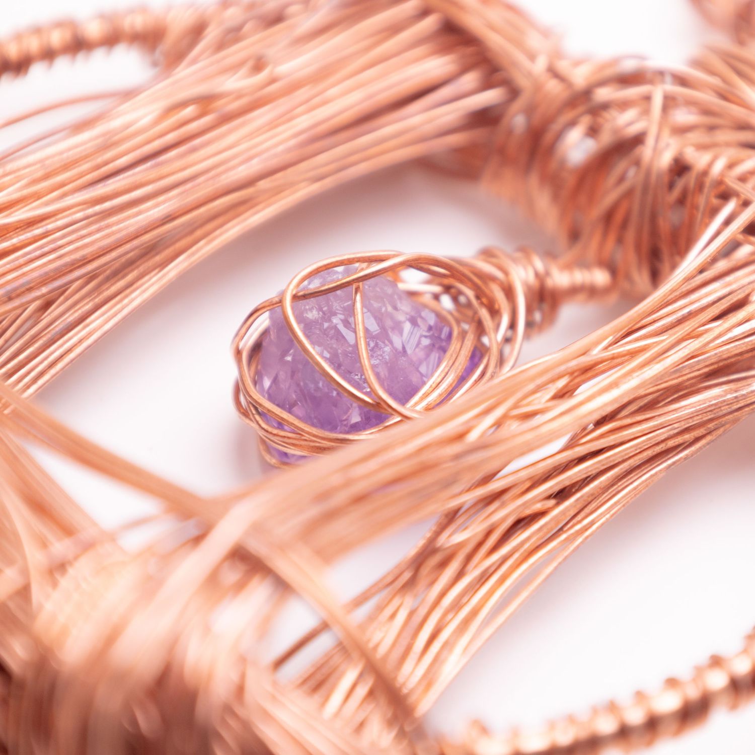 Rose gold copper wire wrapped pendant featuring a faceted purple amethyst gemstone centerpiece.