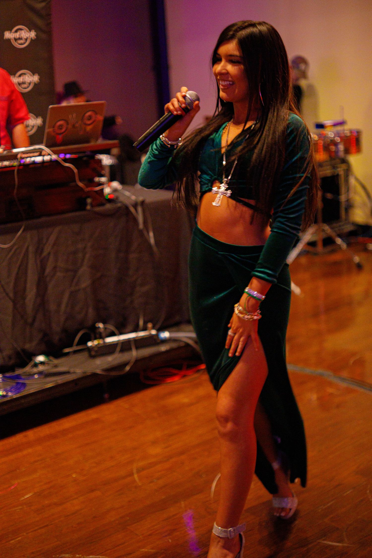 Woman in green velvet outfit performs on stage at Hard Rock venue.