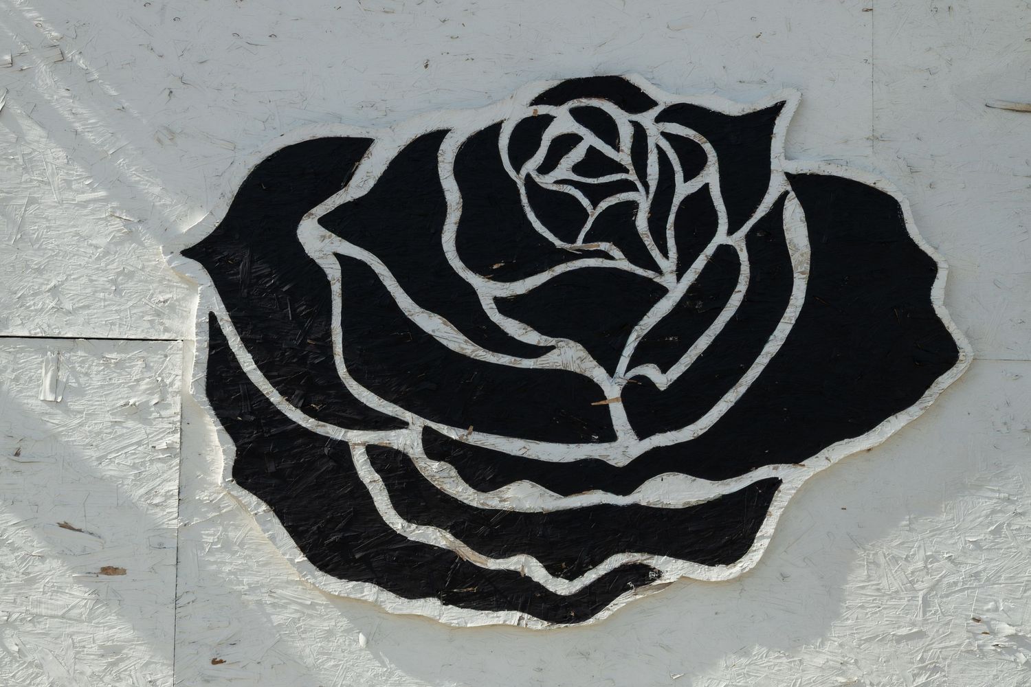 Black and white mosaic rose artwork on a gray wall, featuring bold outlines and intricate petal details.
