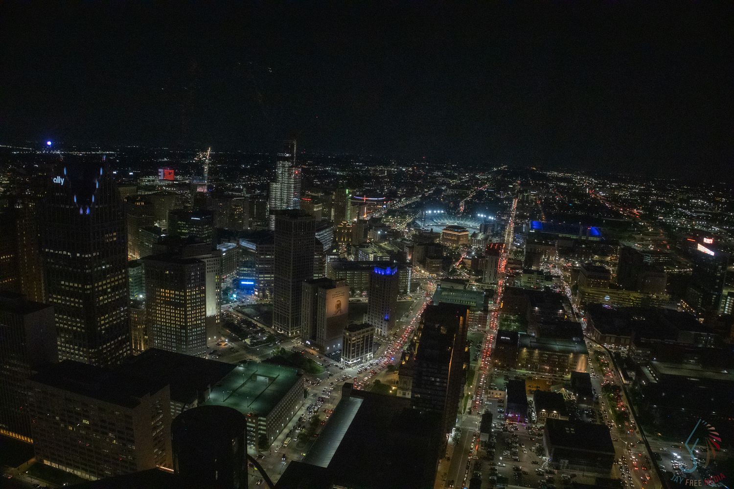 Aerial night view of a city skyline with illuminated streets and buildings stretching into the distance.