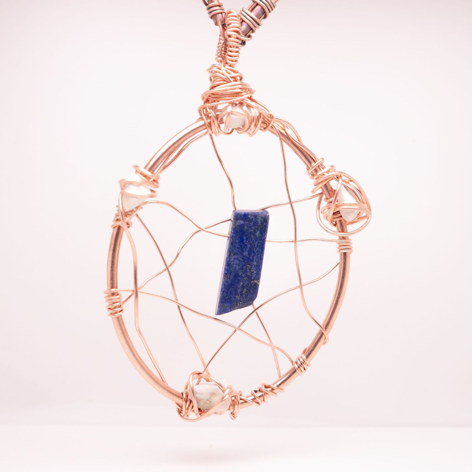 Handcrafted rose gold wire wrapped oval pendant with blue lapis lazuli stone centerpiece.
