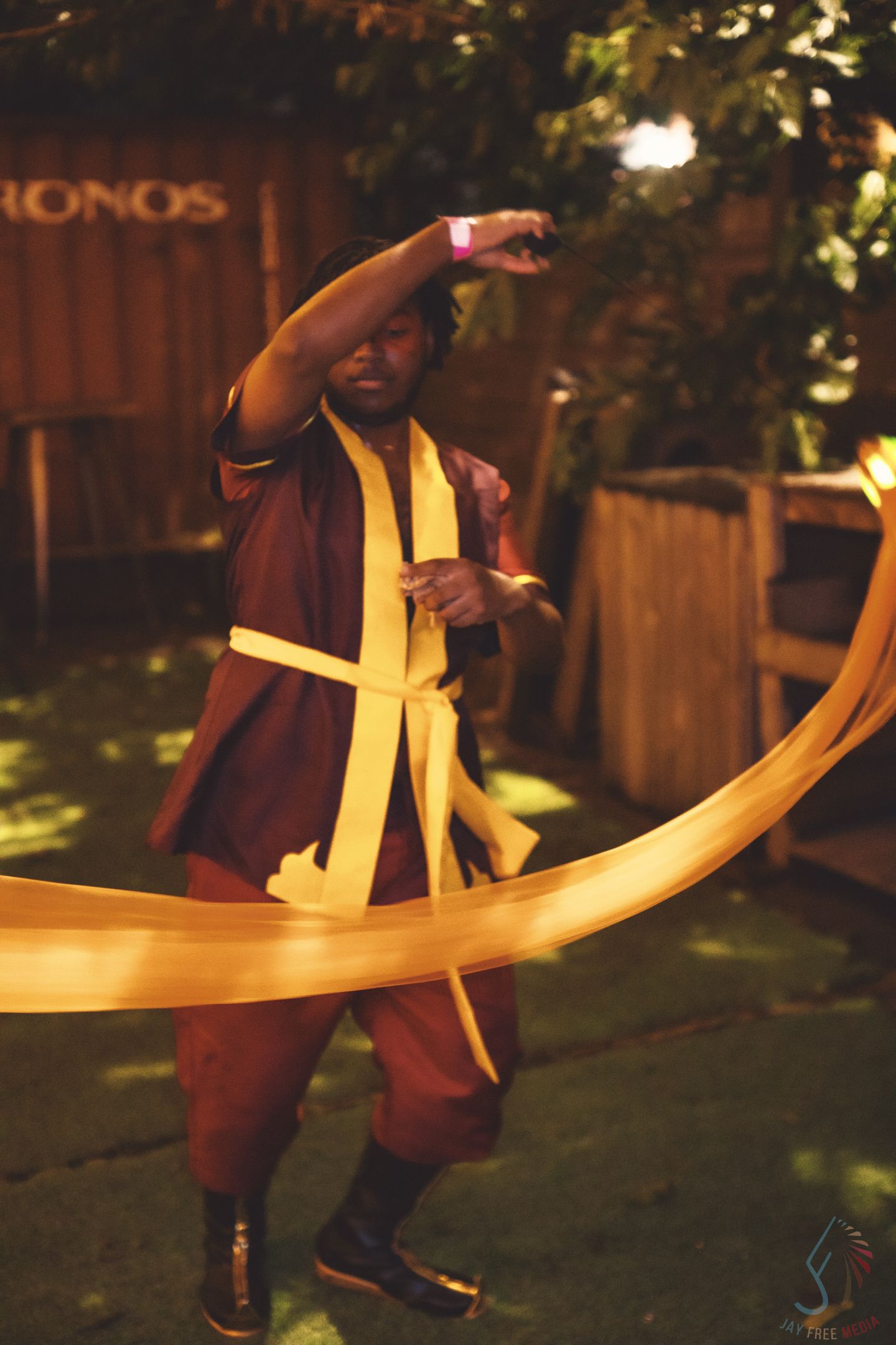 A dancer performs with a curved golden prop in a nighttime outdoor setting.