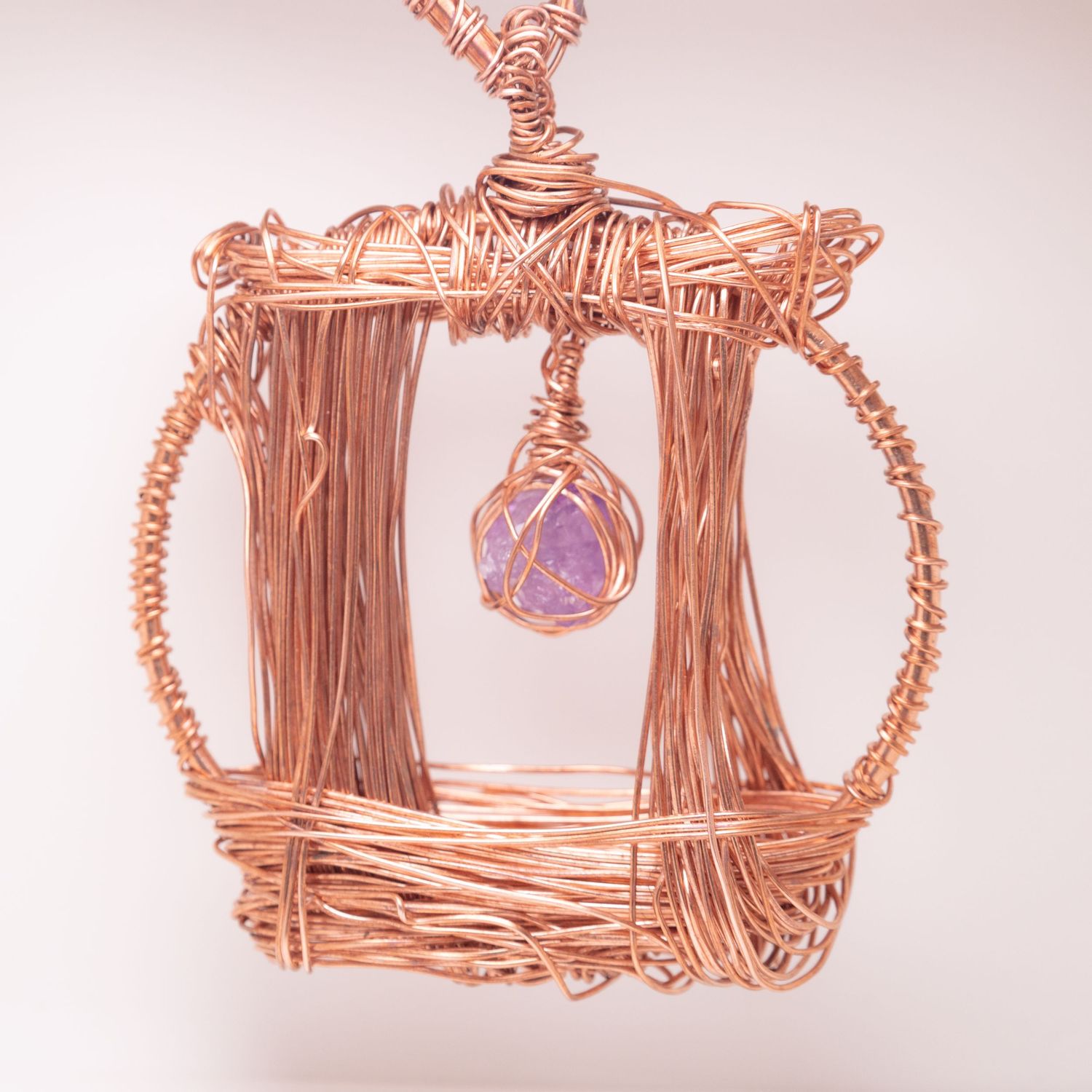 Handmade copper wire wrapped pendant featuring a rectangular frame with circular sides and a purple gemstone centerpiece.