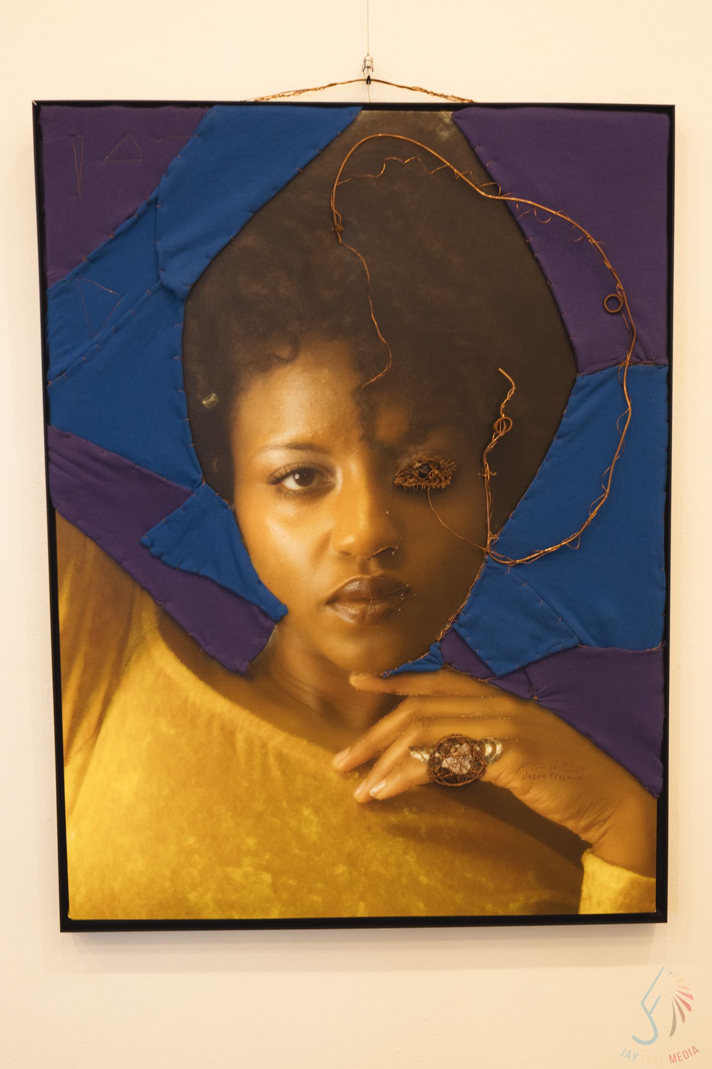 Portrait-style artwork with gold and blue tones displayed in a gallery setting.