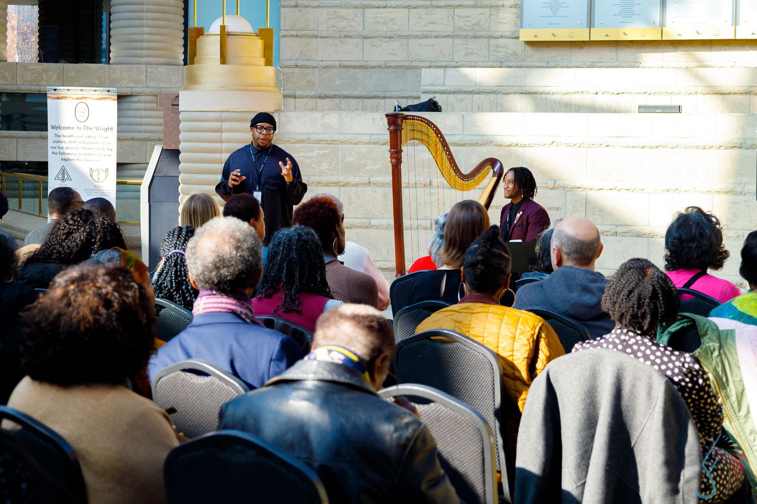 Speaker addresses a diverse crowd outdoors at the Charles H. Wright Museum of African American History event.