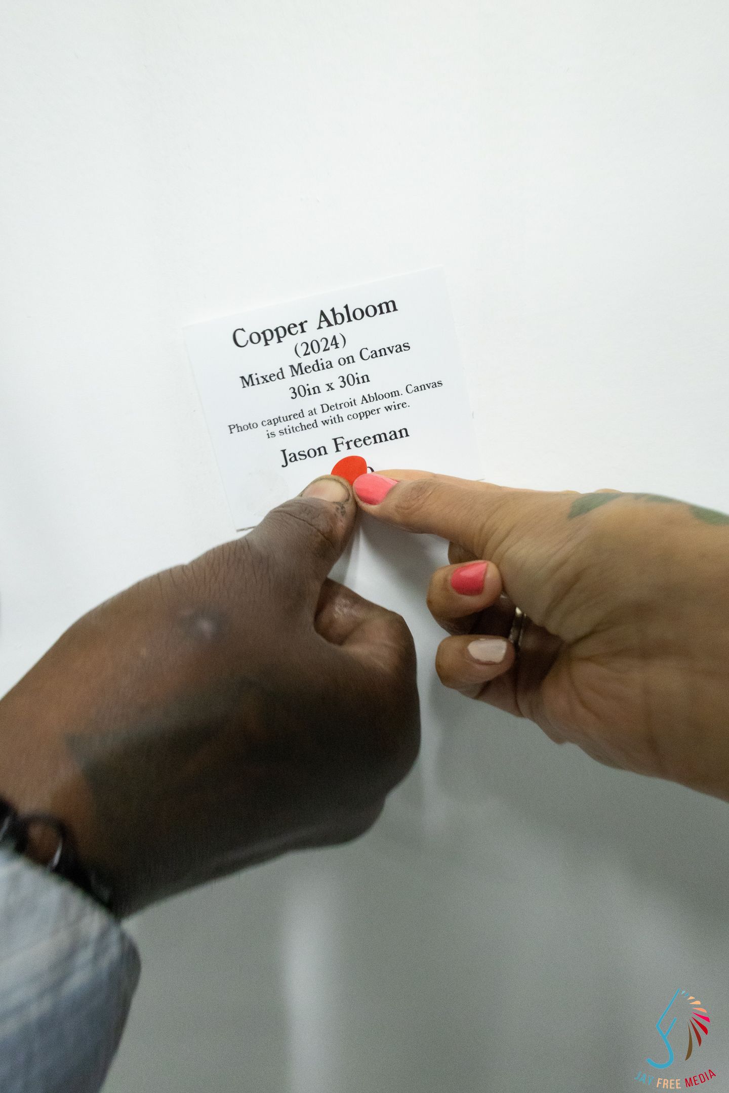 Hands pointing to artwork label for Copper Abloom 2024 by Jason Freeman.
