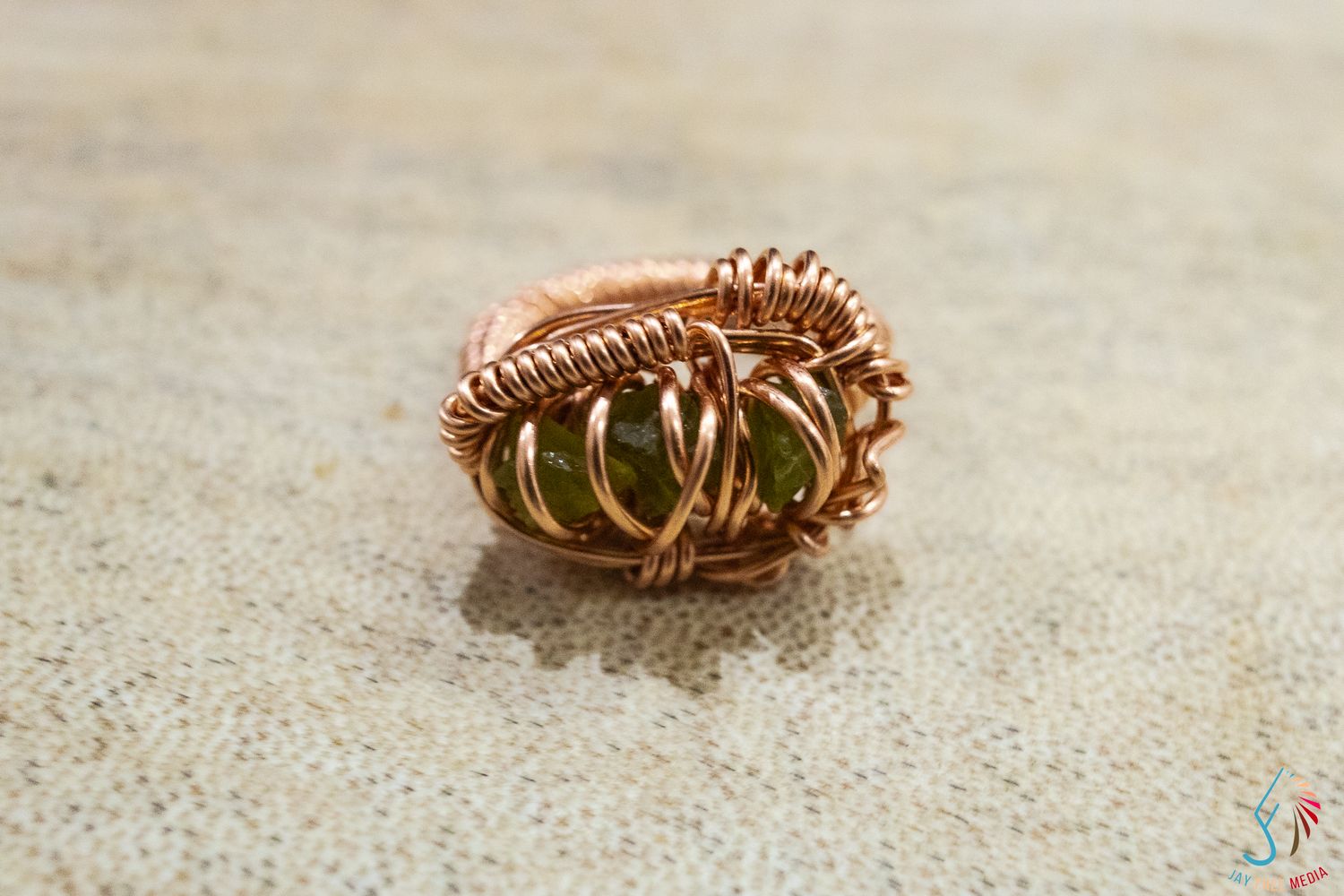 Handmade copper wire wrapped ring featuring a green gemstone, crafted with intricate coiling details.
