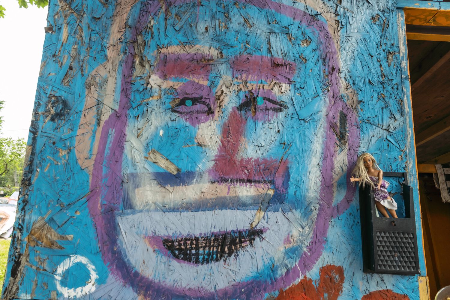 Colorful street art mural of a large blue face with expressive features painted on a building exterior.