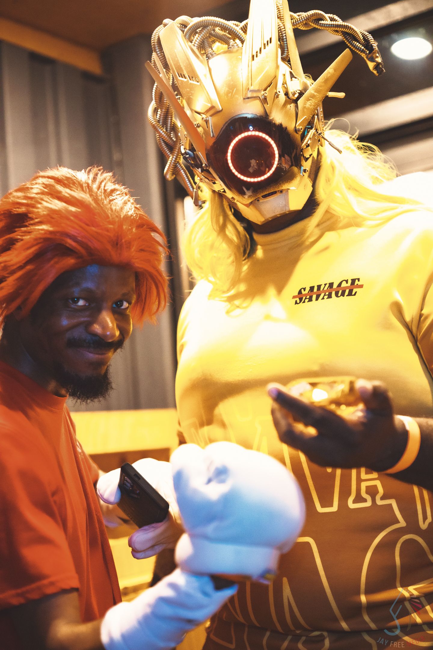 A performer in a yellow outfit interacts with a glowing prop under dramatic lighting.