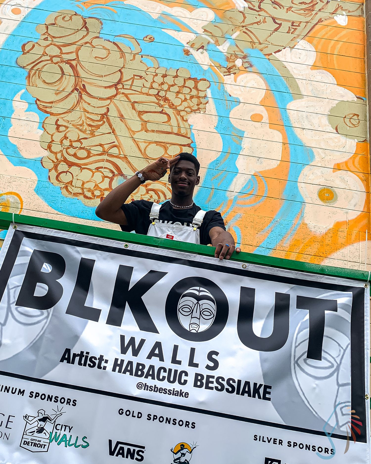 Artist Habacuc Bessiake poses in front of his colorful mural at BLKOUT Walls street art festival in Detroit.