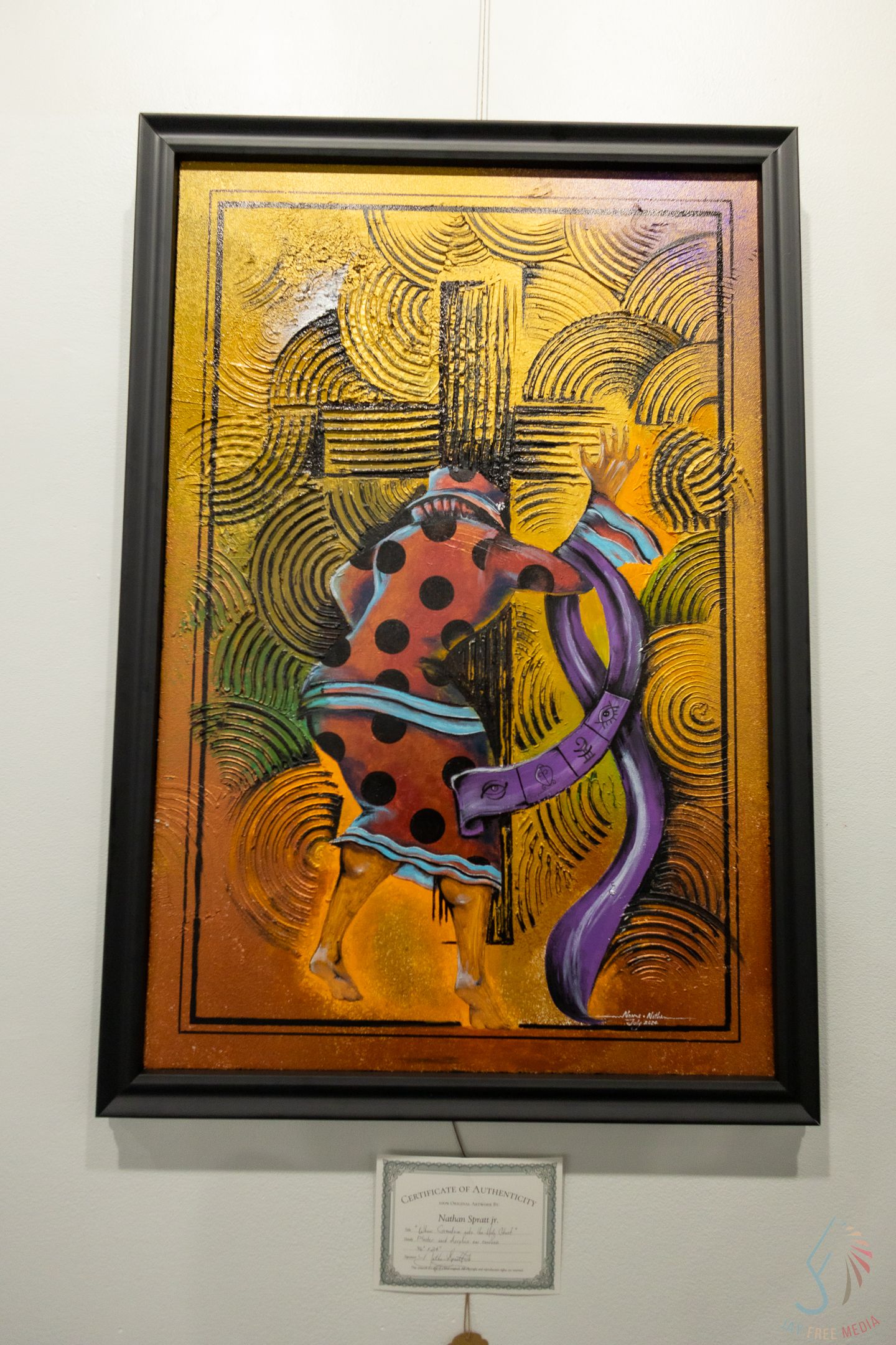 Colorful painting of a dancer in red polka dot dress with purple ribbon against golden background in black frame.