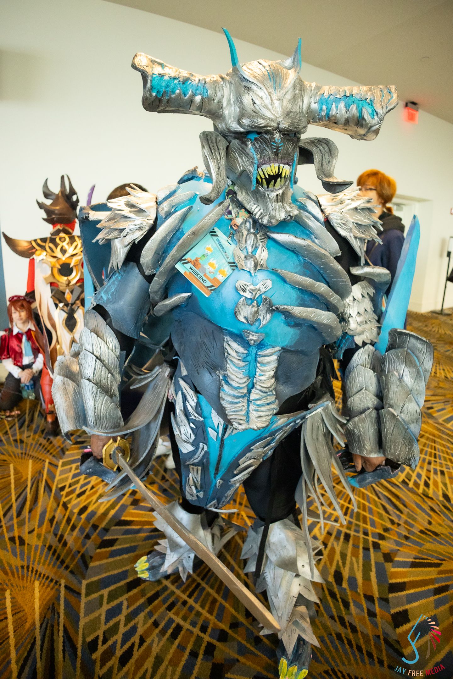 Elaborate blue and silver monster cosplay costume with horns and armor at a comic convention.