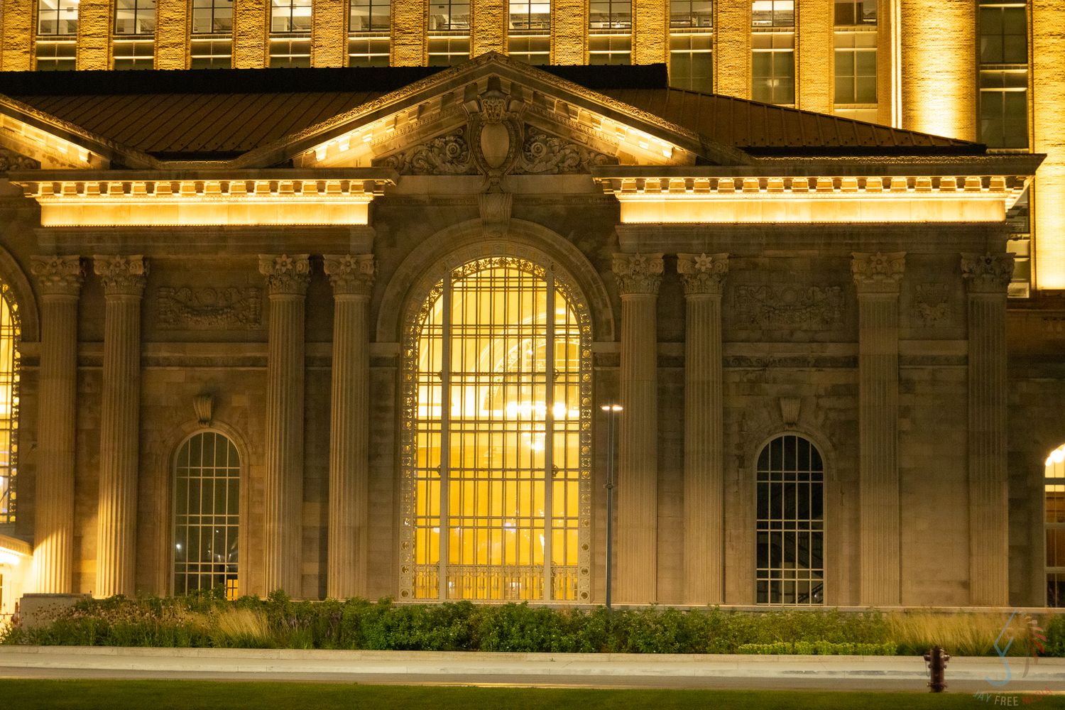 Illuminated neoclassical building facade with arched windows glowing golden at night.
