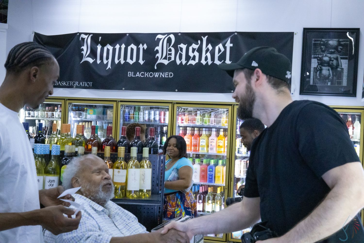 People interacting inside a Black-owned Liquor Basket store with shelves of bottles in the background.