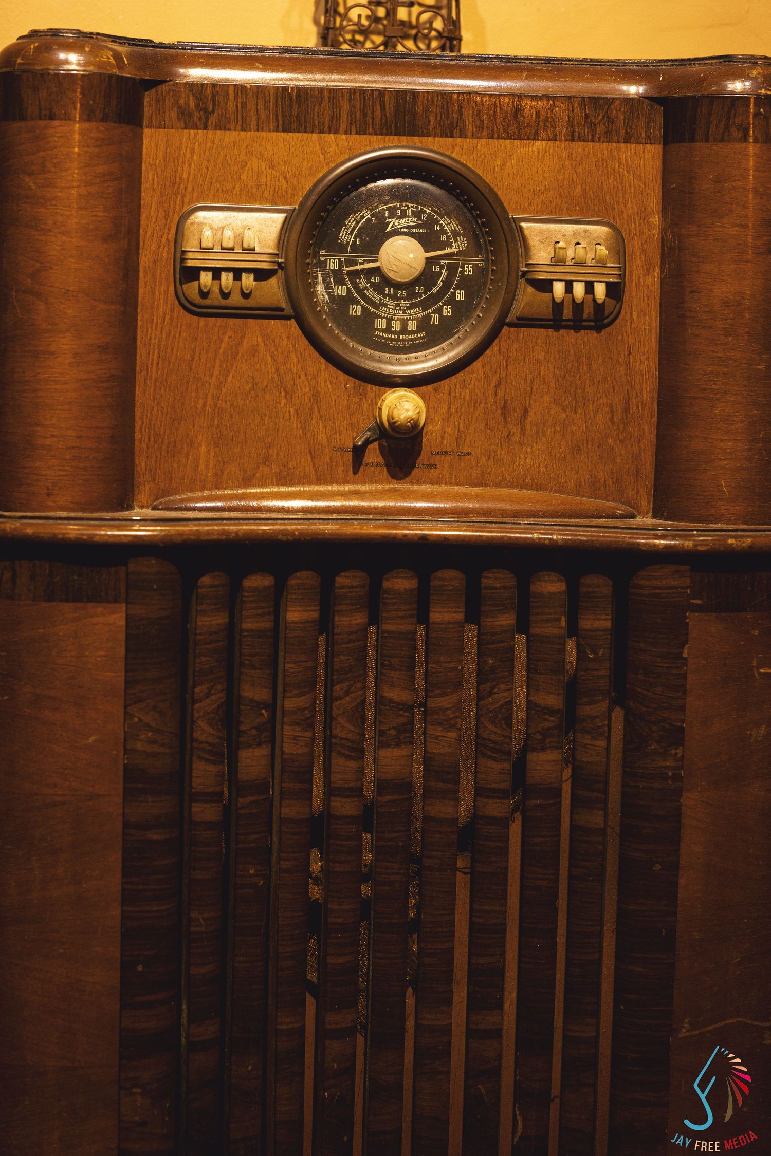 Vintage wooden floor radio cabinet with Art Deco design, circular tuner dial, and decorative speaker grille.