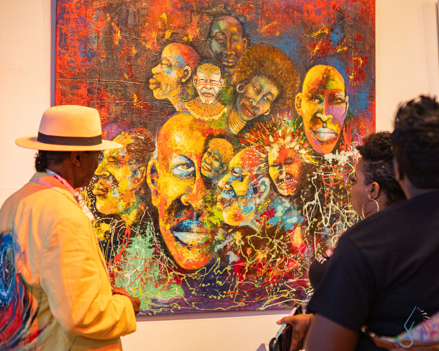 Two visitors admire a vibrant, colorful painting of expressive faces at an art gallery exhibition.