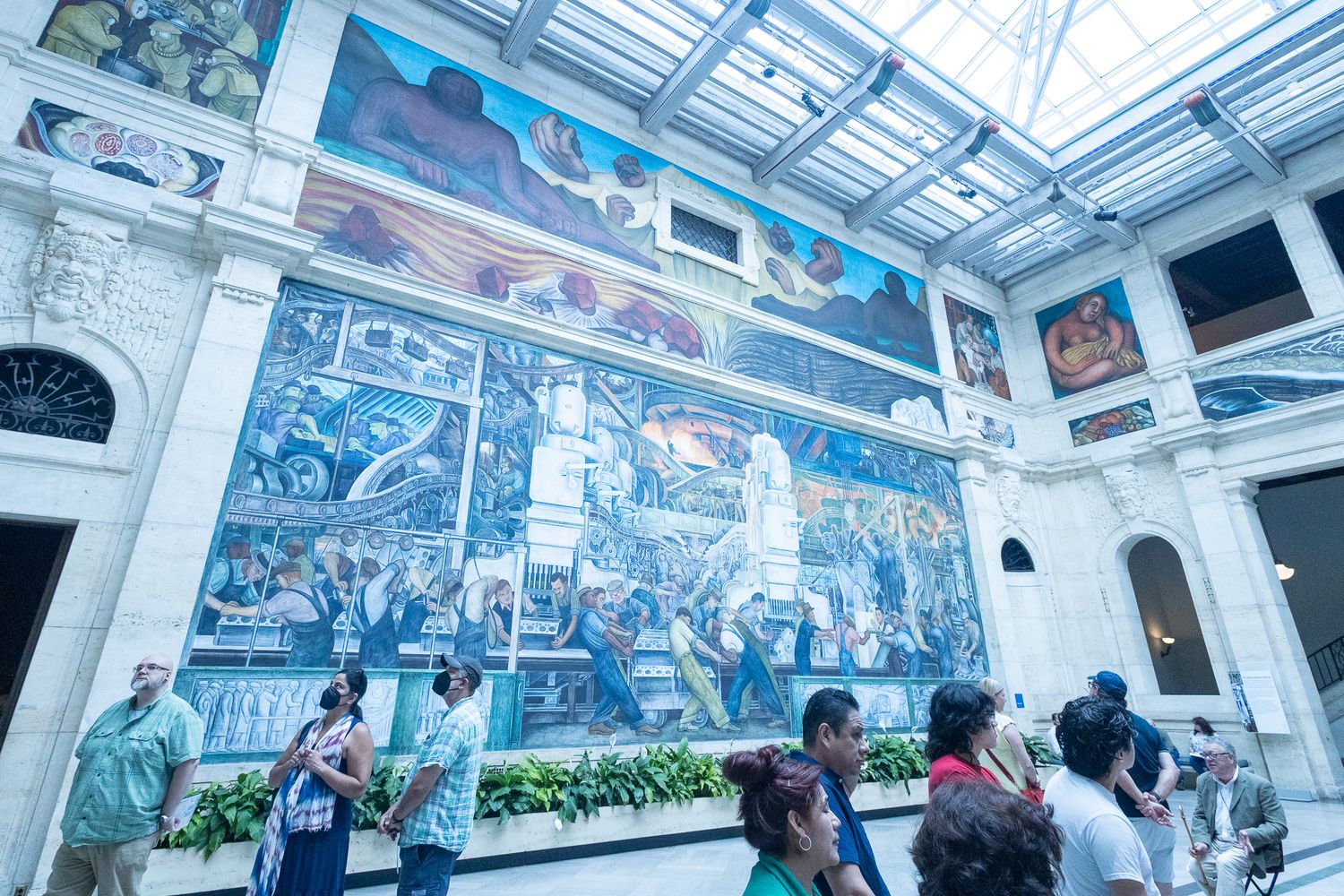 Visitors admire Diego Rivera's massive Detroit Industry Murals under a glass ceiling at the Detroit Institute of Arts.