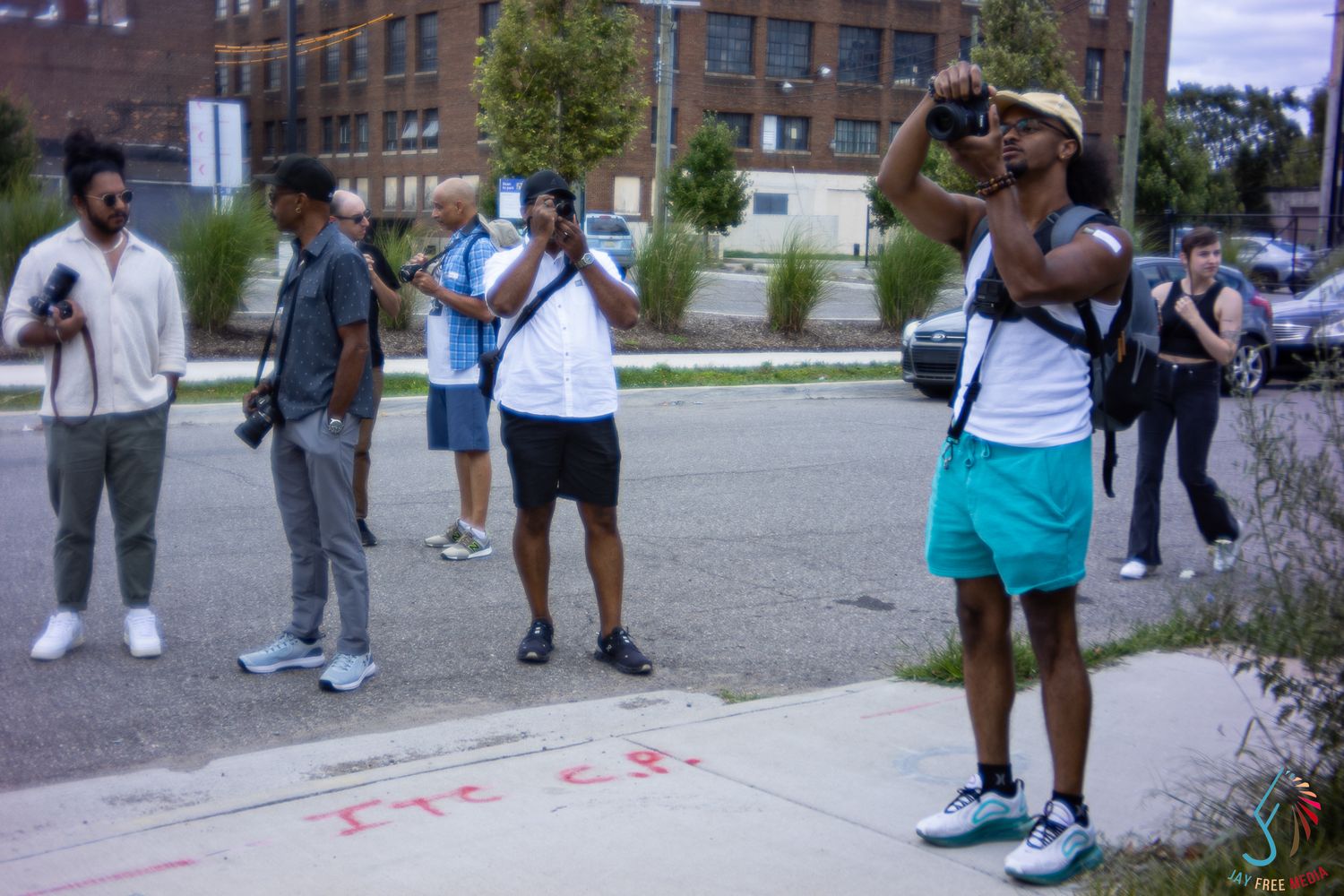 Group of young men photograph urban street art and surroundings on a sunny day in a city neighborhood.