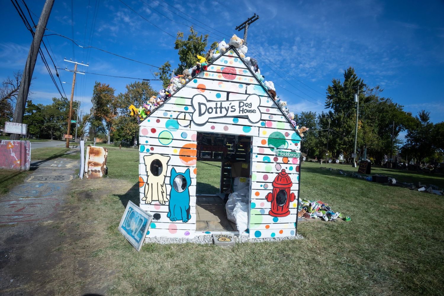 Colorful painted playhouse named Dotty's Place with whimsical art on green grass under blue sky.