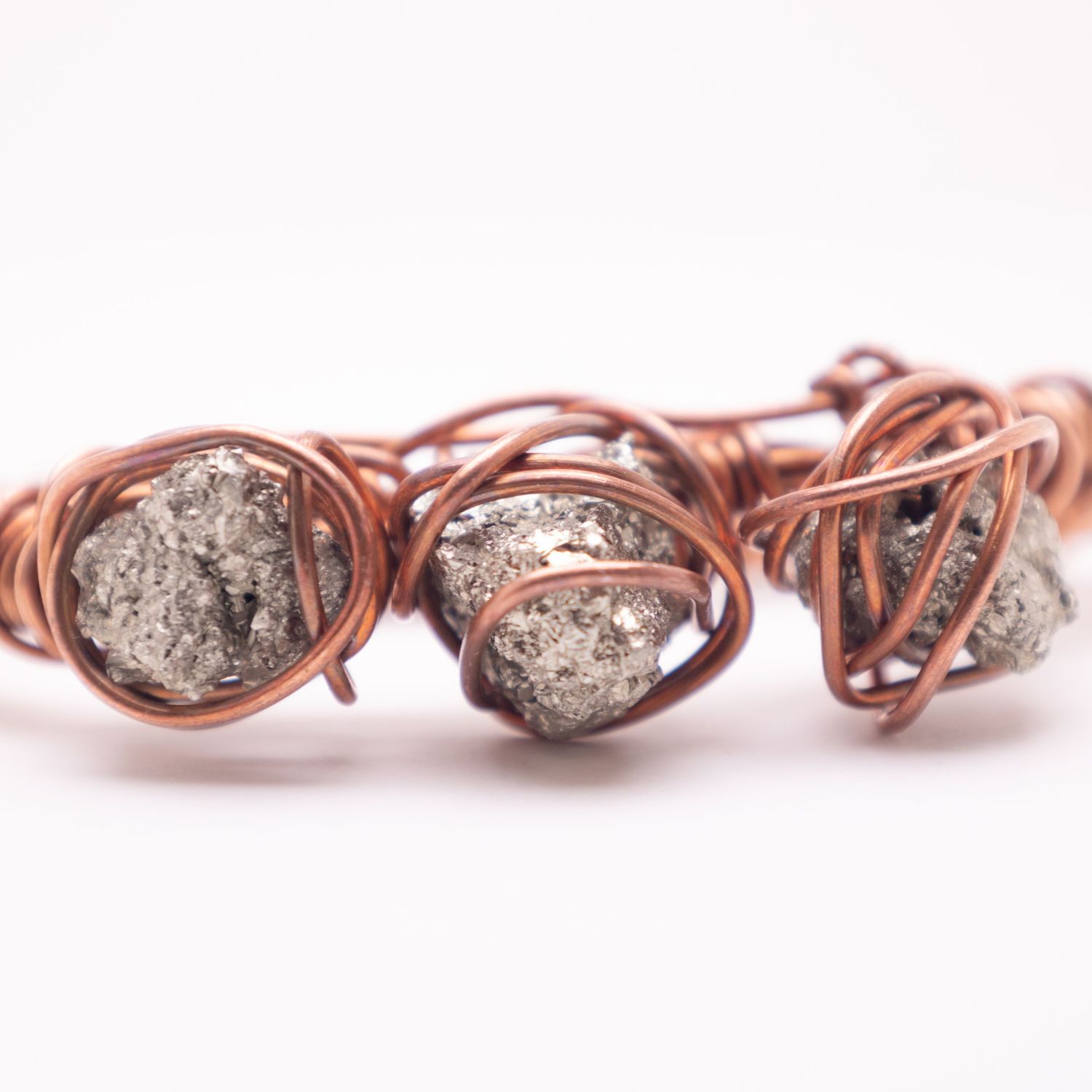 Handmade copper wire wrapped bracelet featuring raw pyrite stones with metallic shimmer on white background.