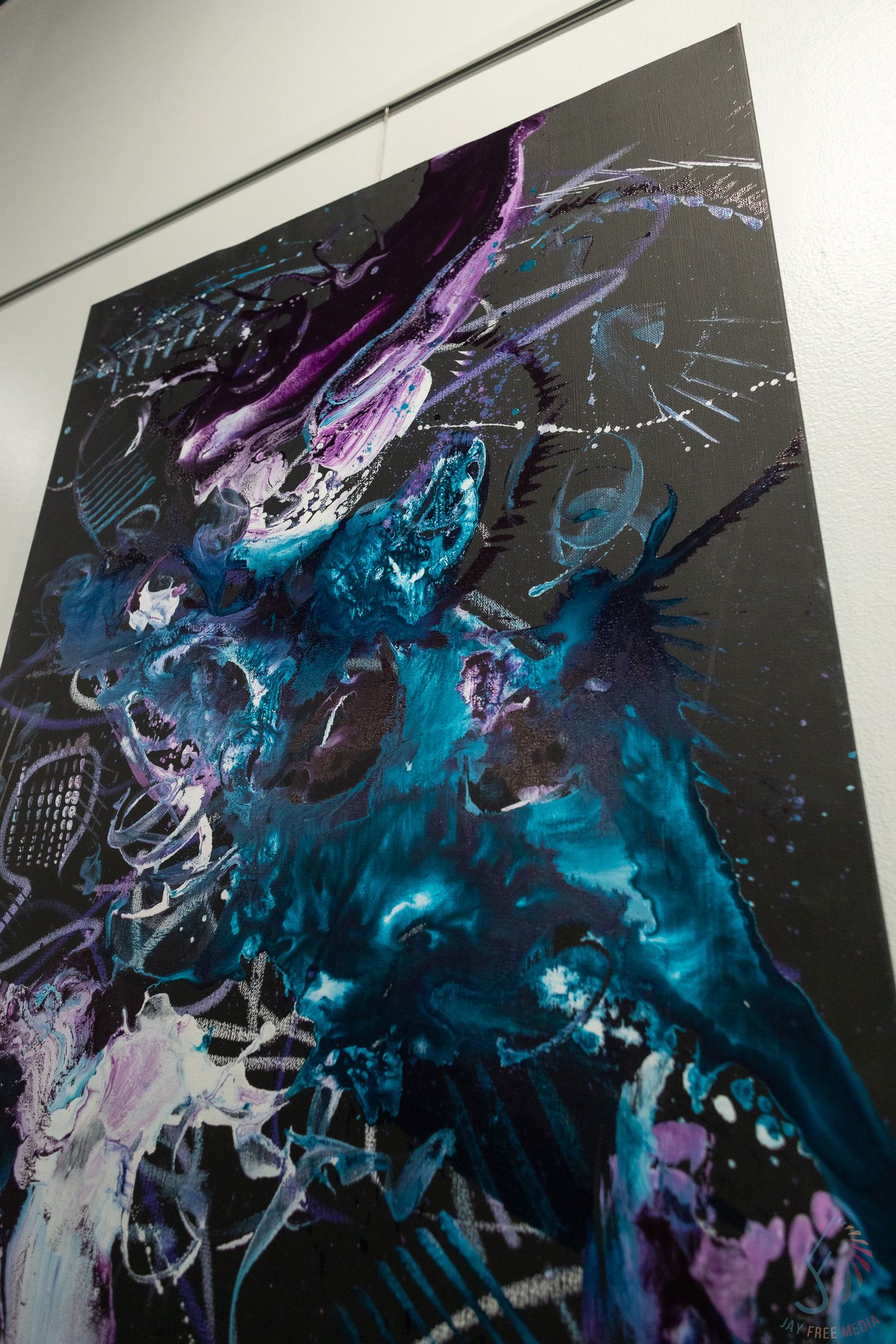 Abstract painting with swirling teal, purple, and white brushstrokes on a dark black background in an art gallery.