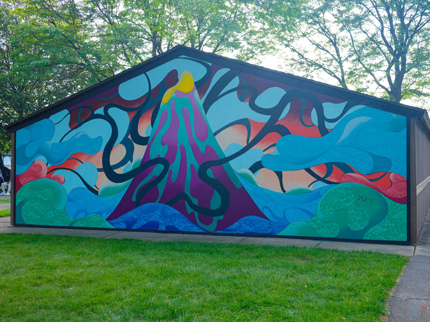 Colorful outdoor mural on building featuring volcanic mountain, abstract trees, and fish in vibrant blues, purples, and pinks.