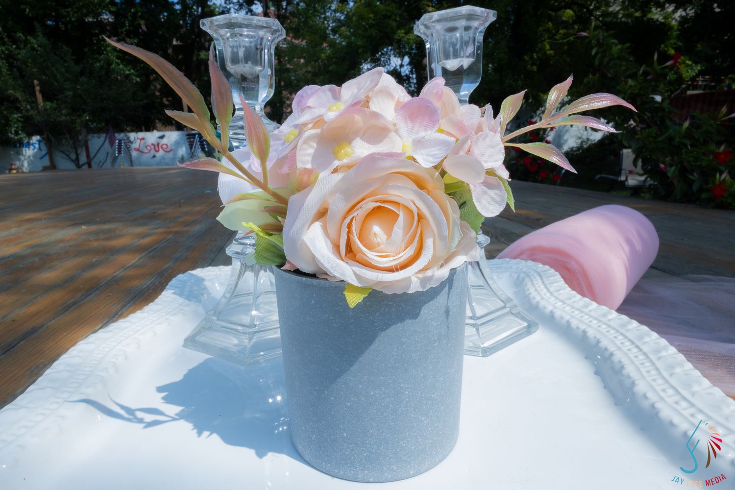 Elegant floral arrangement with pink roses and hydrangeas in a silver tin vase on a white table.
