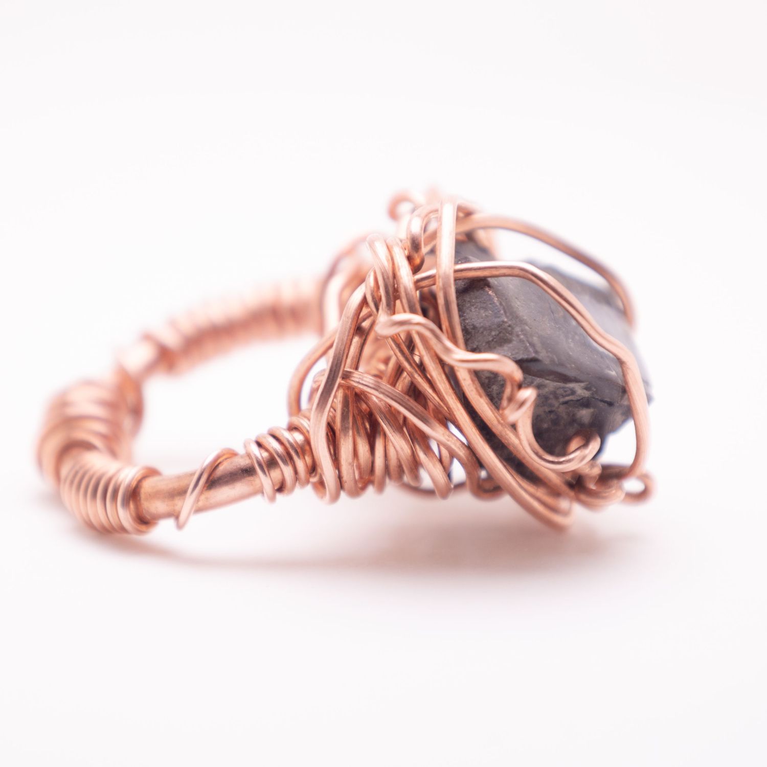 Copper wire wrapped ring featuring a dark smoky gemstone, handcrafted with intricate coiling details.