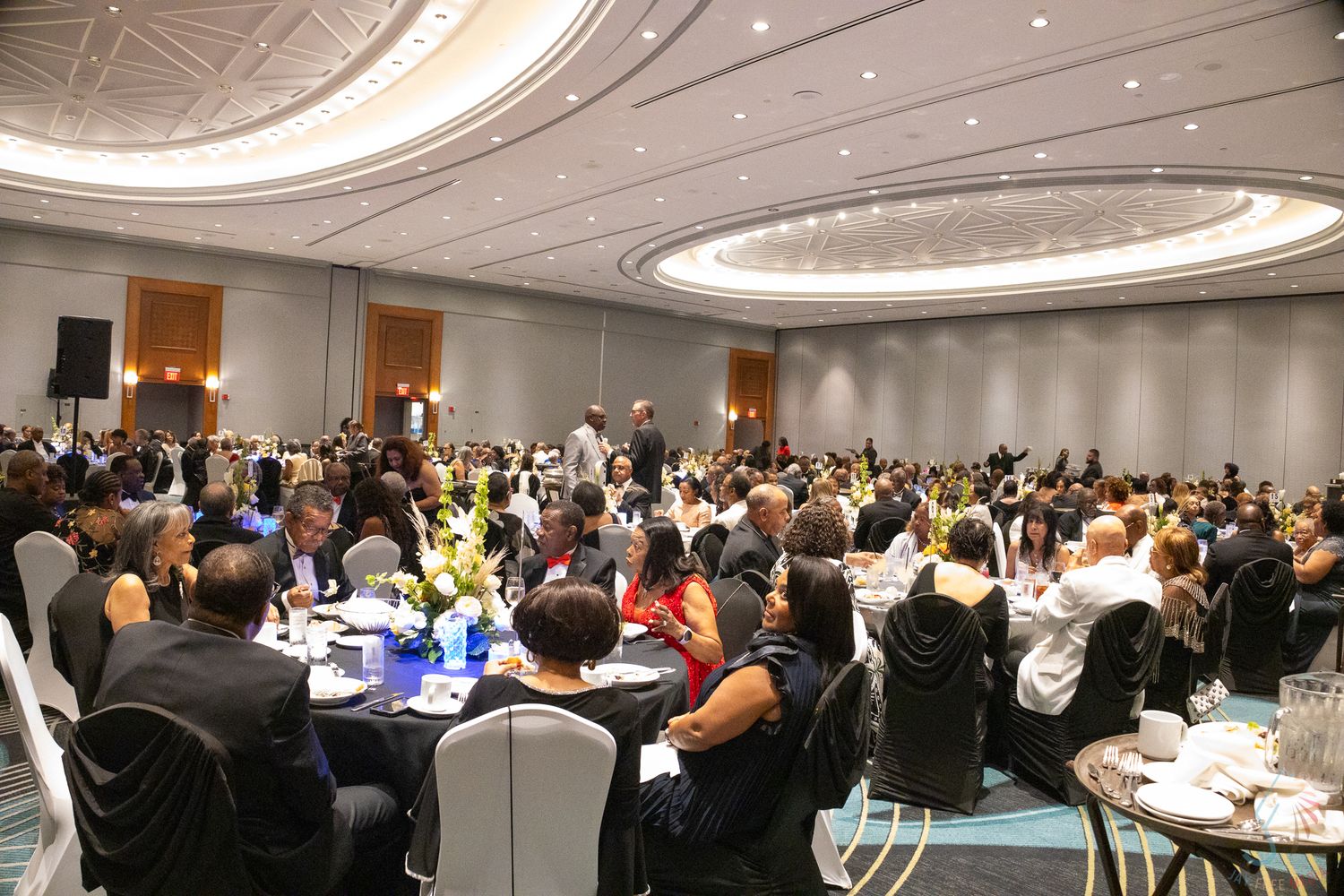 Large elegant ballroom filled with diverse guests seated at round tables during a formal gala or awards ceremony.