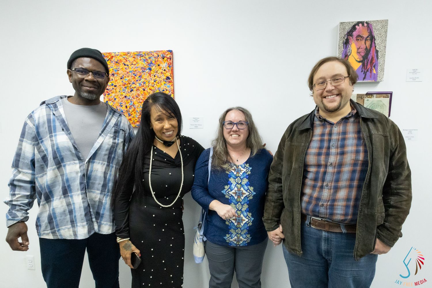 Four people smiling together at an art gallery exhibition opening.