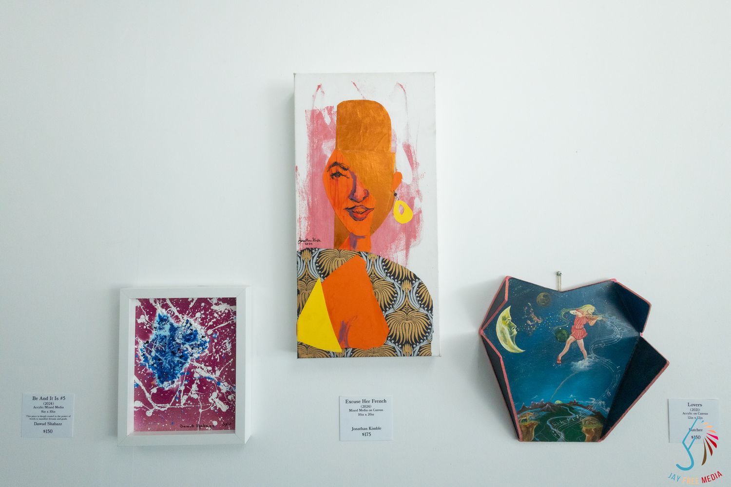 Three mixed media artworks displayed on white gallery wall with labels.
