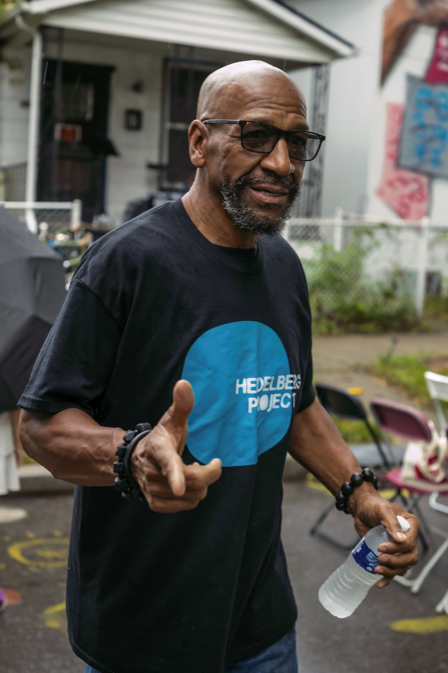 Man in Heidelberg Project black t-shirt giving thumbs up outdoors.