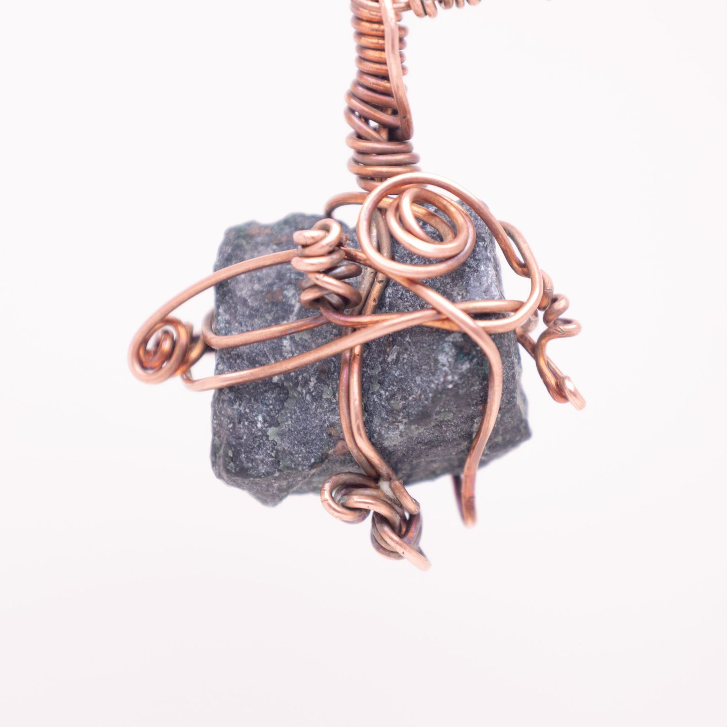 Handmade copper wire wrapped pendant featuring a rough gray stone with decorative swirl details.