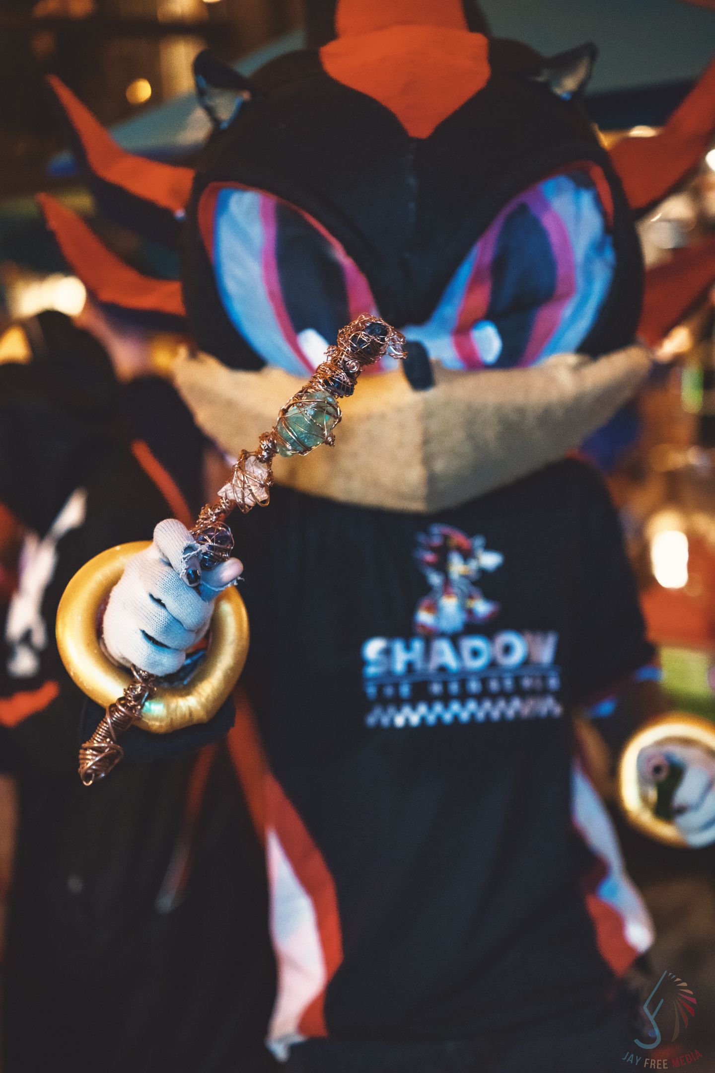 Person in Shadow the Hedgehog fursuit costume holding a decorative crystal wand at a convention.