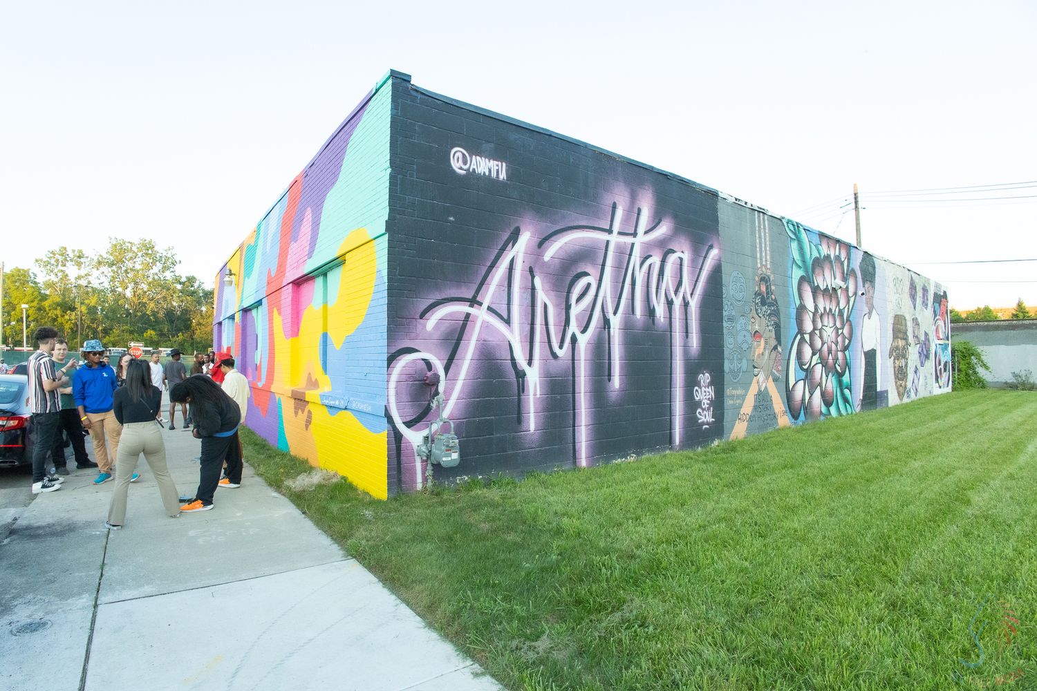 Colorful mural on brick building featuring the name Aretha in graffiti-style lettering with floral designs.