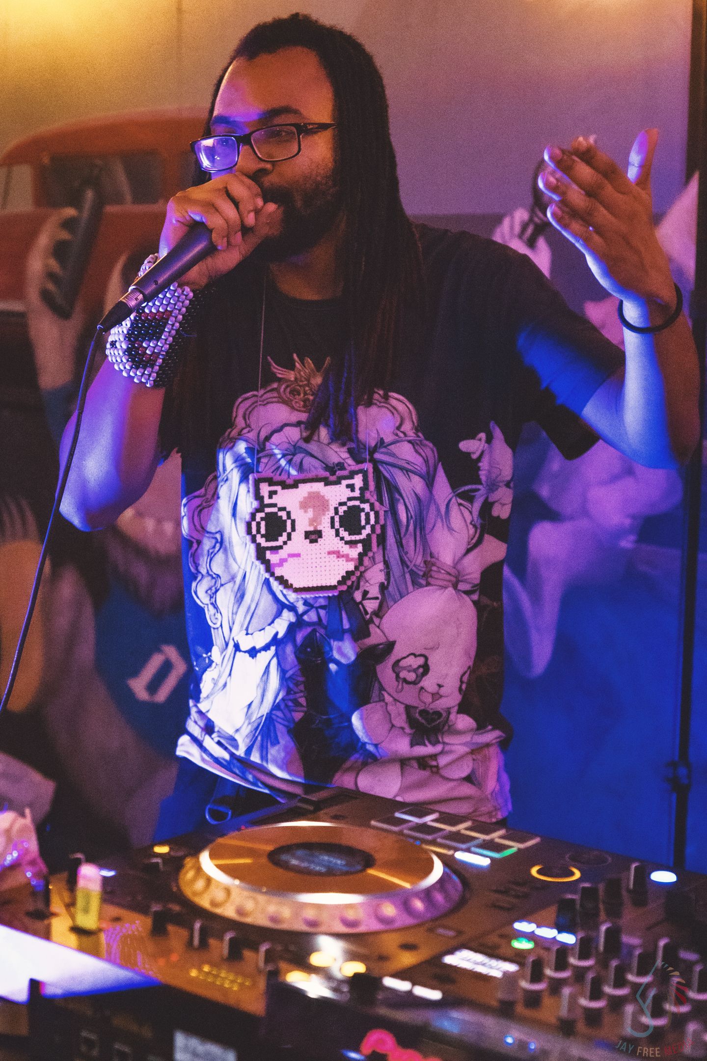 DJ performing at a nightclub with purple lighting and electronic equipment.