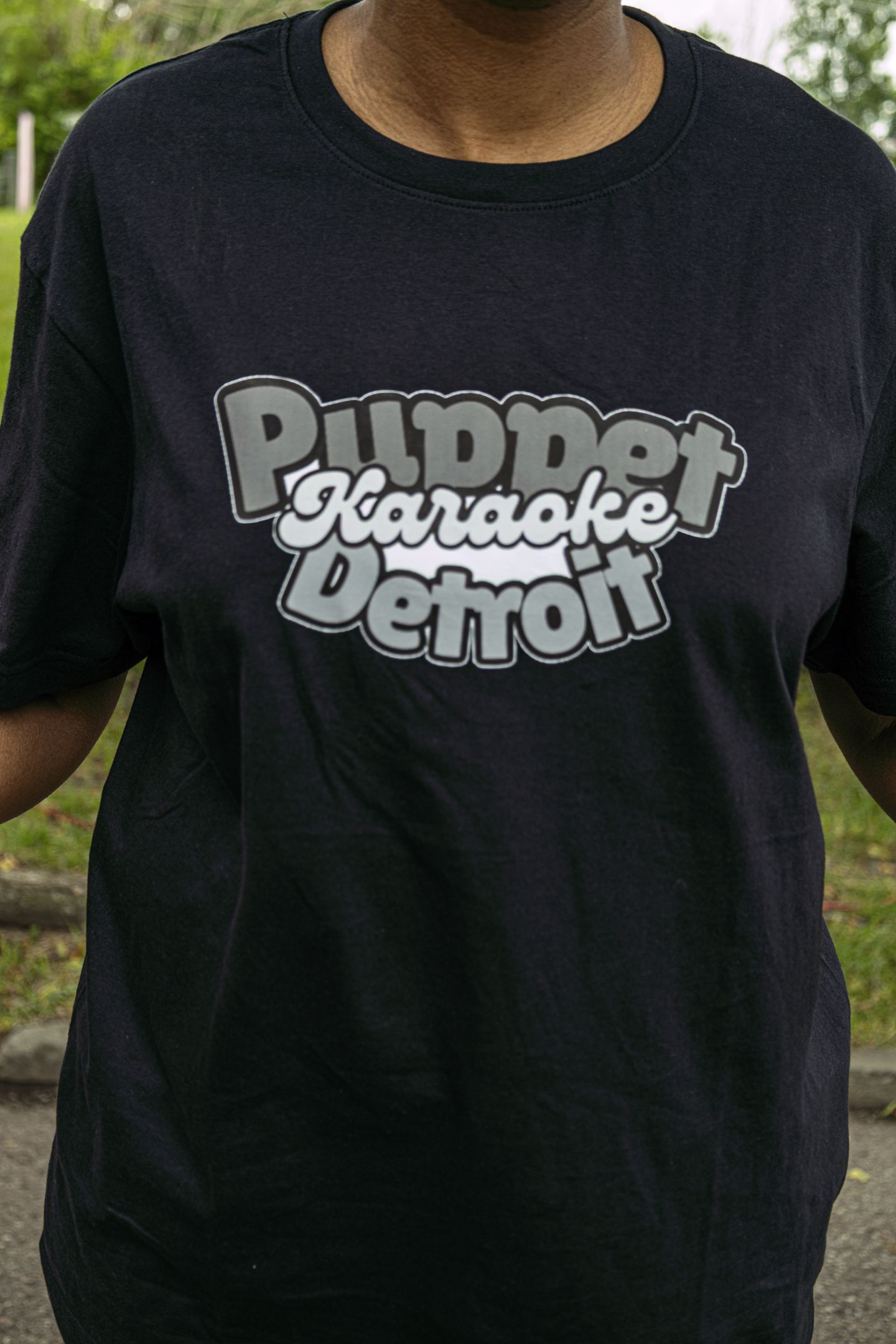 Black t-shirt with Puppet Karaoke Detroit logo in gray and white retro typography.