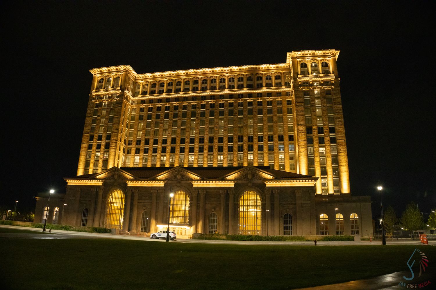 Historic Michigan Central Station illuminated in golden light at night, showcasing Beaux-Arts architecture in Detroit.